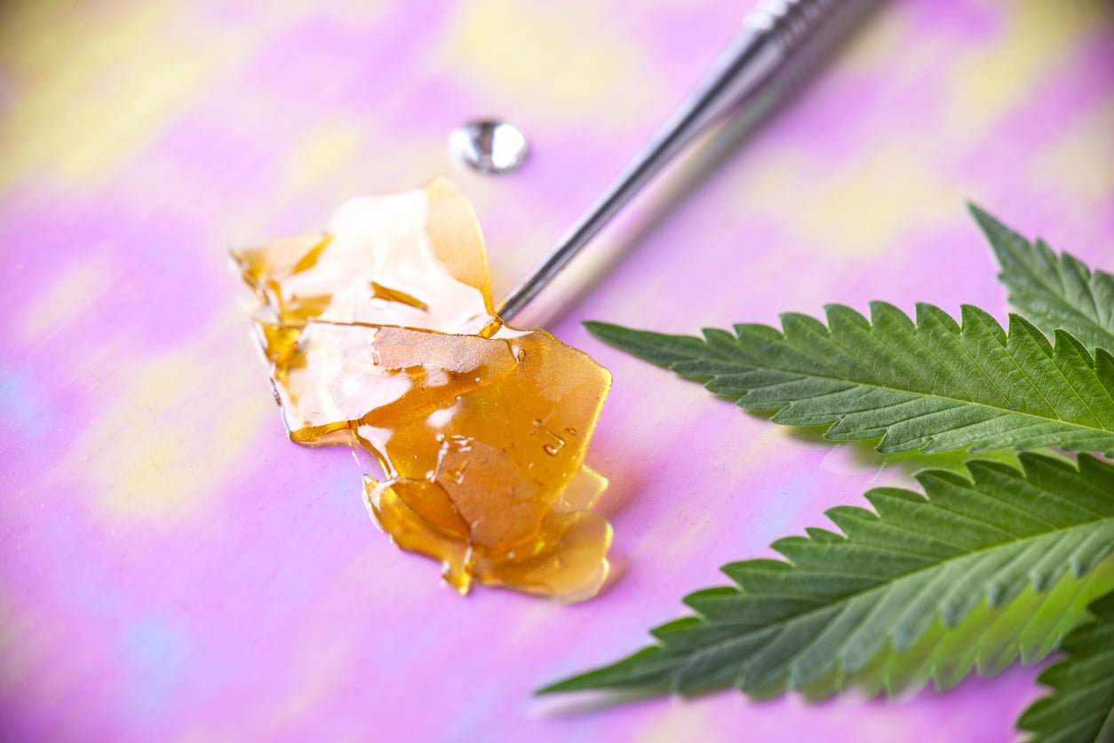 Macro detail of dab tool with cannabis concentrate aka shatter and marijuana leaf, cannabis extraction concept