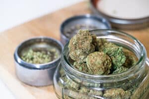 THC and CBD flower buds of Cannabis recreational and medical marijuana , jars of weed overflowing out of glass jar and more weed in the background
